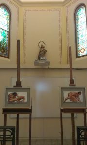El altar de la capilla con la escultura de la Virgen, flanqueada por dos de las obras exhibidas, cuyo motivo de ambas es el desnudo